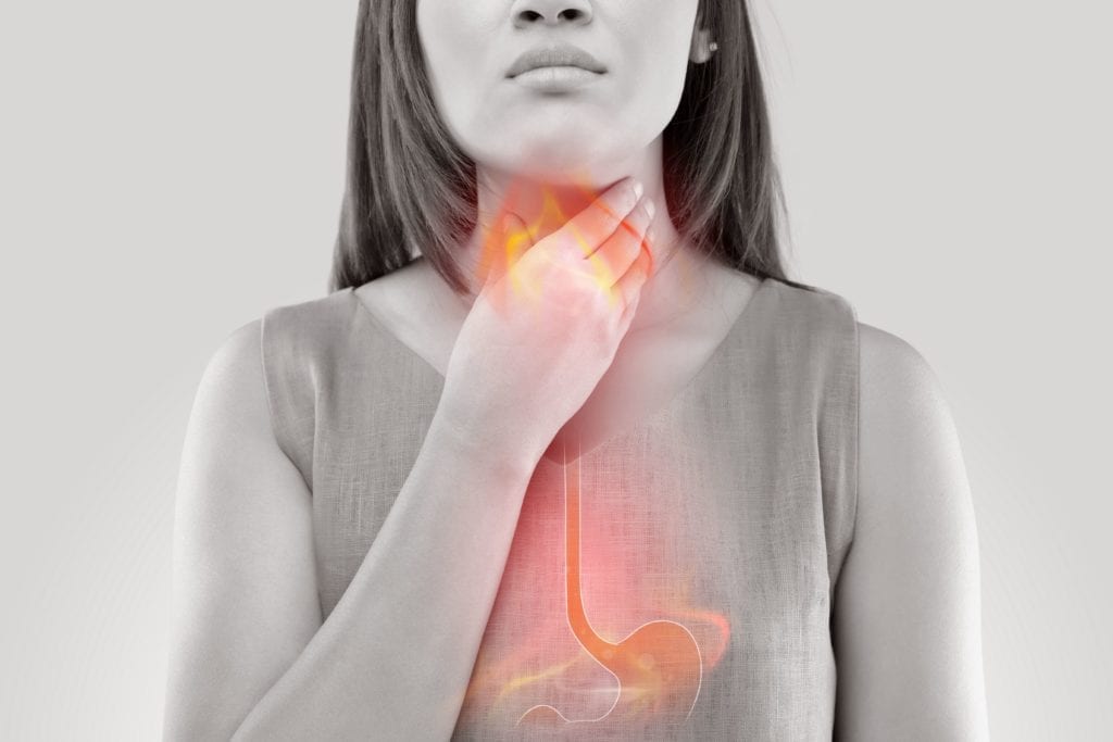 woman with GERD clutching her esophagus
